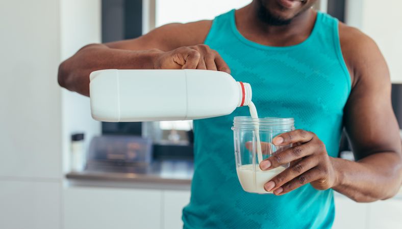 Man pouring milk in a glass after workout