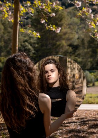 Teenage girl looking at mirror outdoors