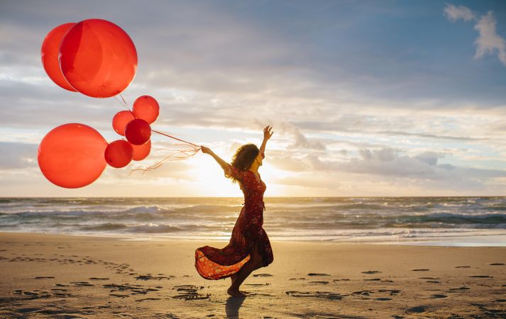 Young woman celebrating with balloons on a beach