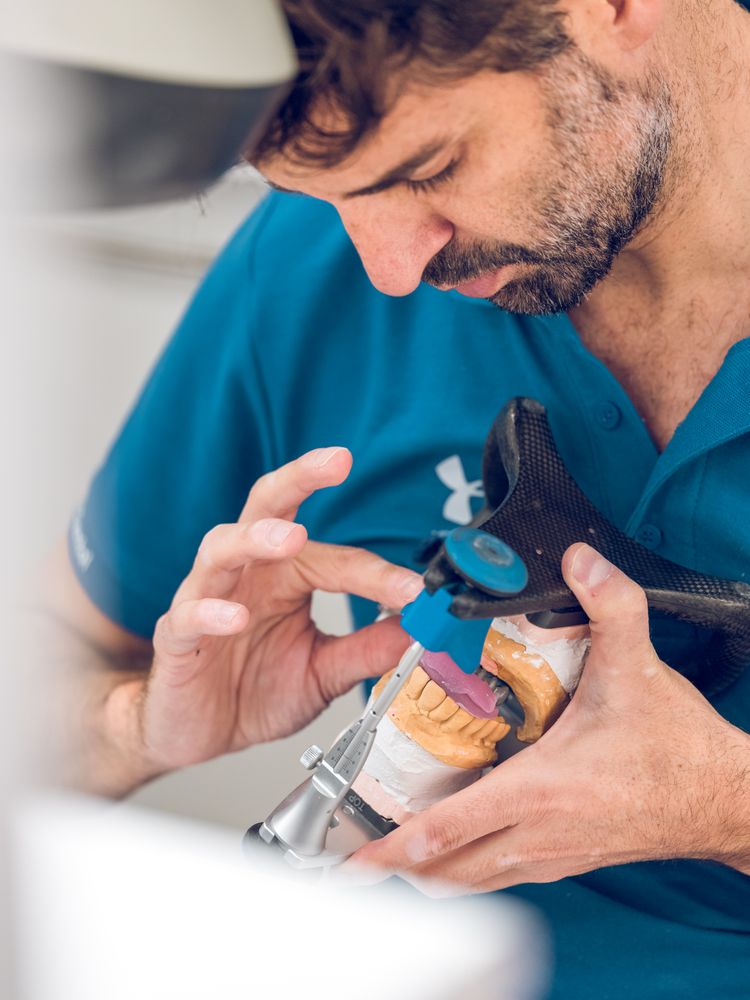 Bearded orthodontist examining denture casts in articulator