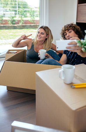 Couple making selfie sitting inside moving box