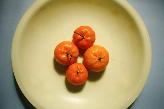 Looking down at four clementines arranged on a plate