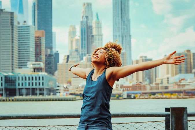 Smiling Black woman with her arms open with Hudson River in the background, copy space