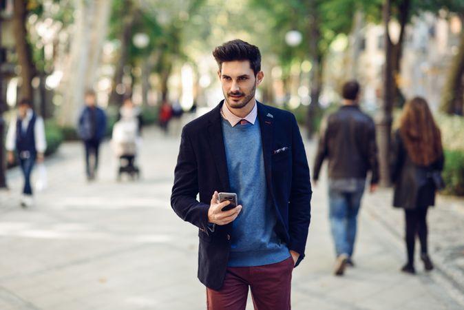 Sharply dressed man in the street wearing suit with smart phone in his hand