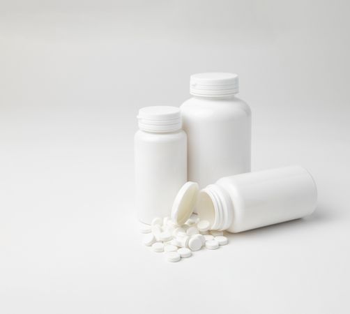 Mockup of a aspirin bottles, different sizes, one lying down open, with copyspace