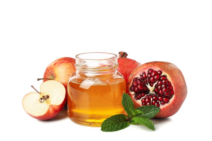 Pot of honey with dipper, open pomegranate and apples
