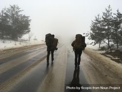 Two people with backpack walking on the road during winter bGGmAb