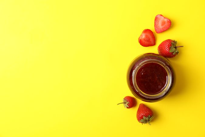 Delicious strawberry jam on yellow background, top view