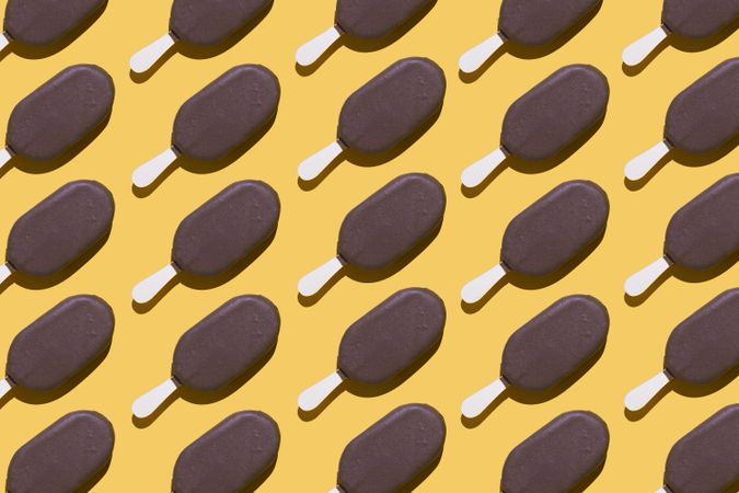 Chocolate popsicle lined up in diagonal order on a yellow background