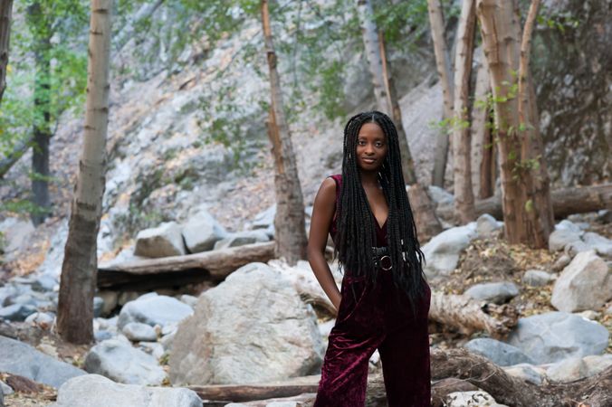 Confident woman standing with her hands in her pockets in front of boulders
