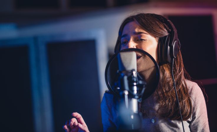 Closeup of woman recording a song for her new album in recording studio