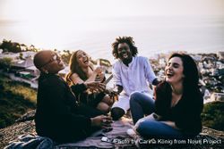 A group of friends laughing and hanging out overlooking the ocean o5oDQ4