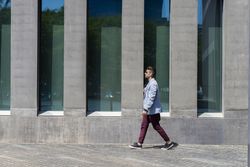 Side view of man walking in the sun outside of building