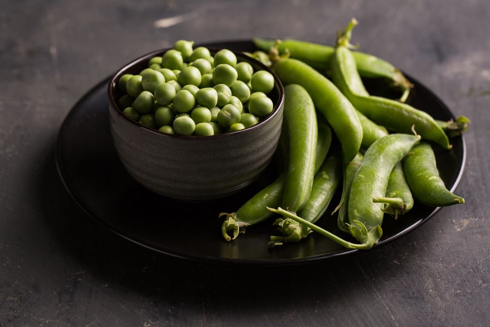 Fresh peas and pea pods on dark background