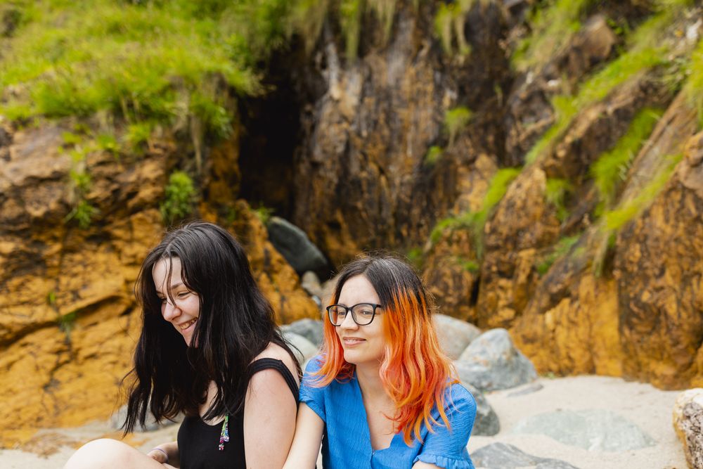 Two young female laugh and happily enjoy a day on a natural beach in summer