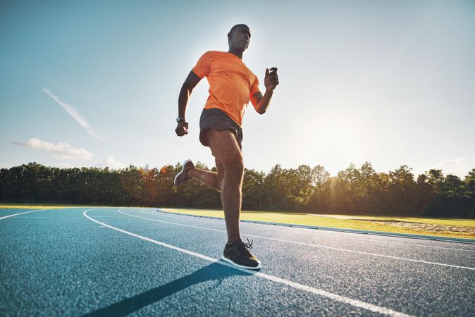 Man running on athletic track on sunny day