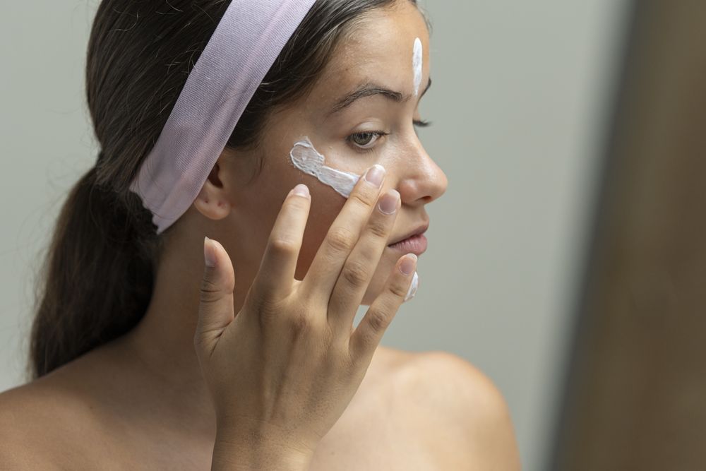 Close up profile of a young woman applying moisturizing cream during her beauty routine