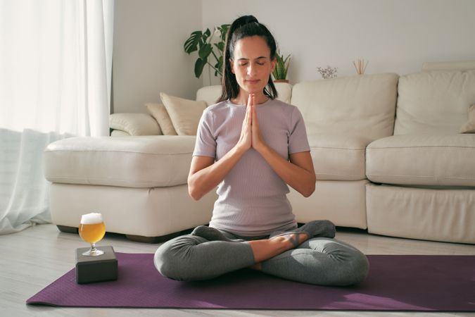 Woman meditating near glass of beer