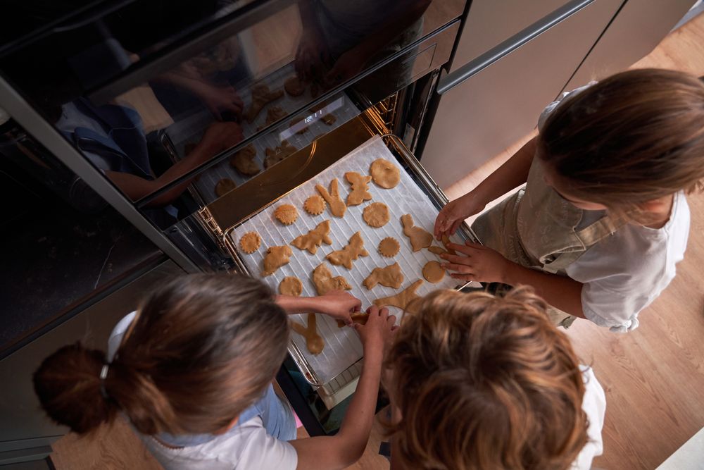 Unrecognizable children arranging cookies on oven rack