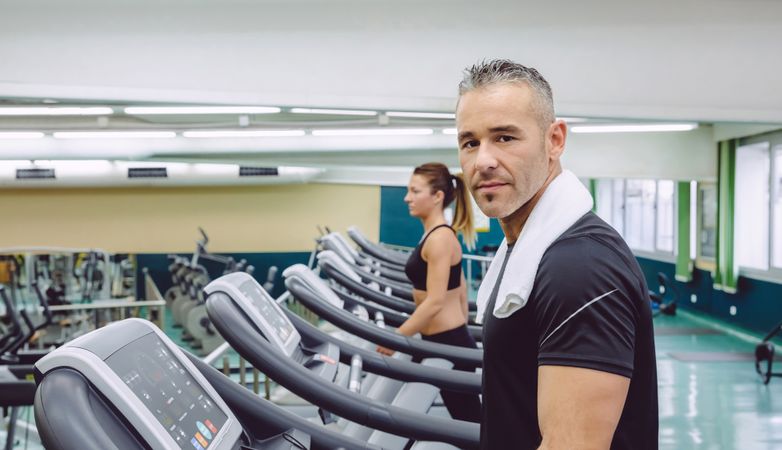 Portrait of man looking at camera from gym treadmills