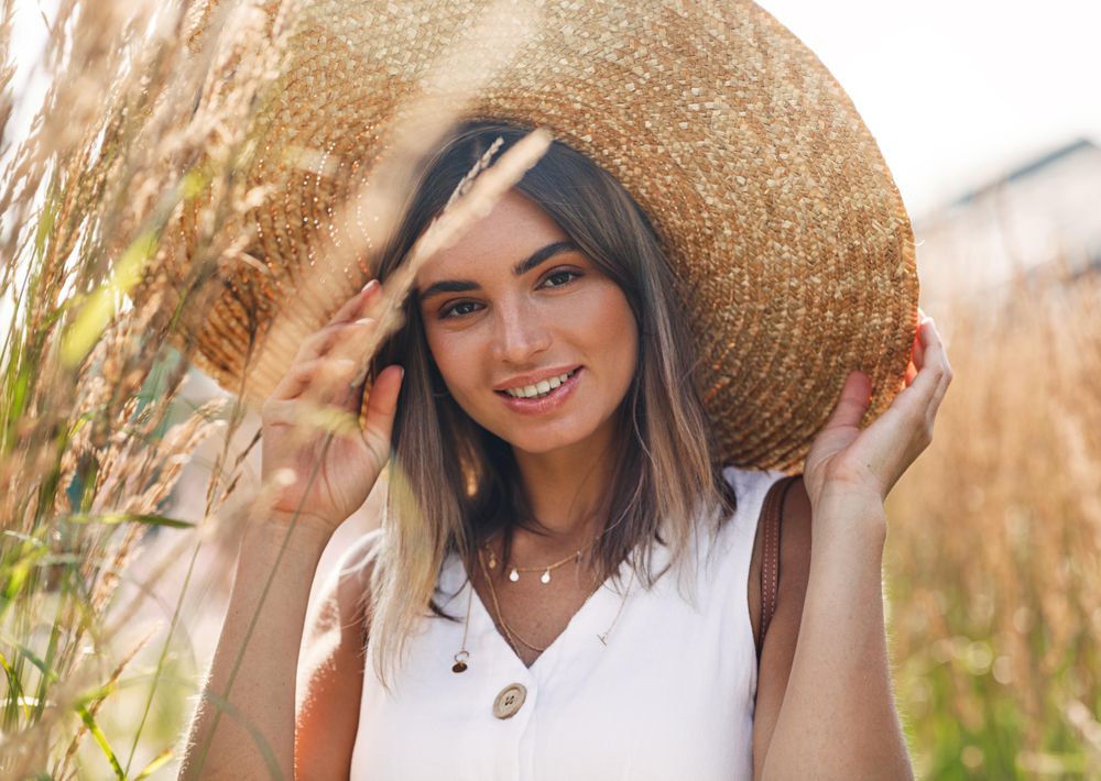 Portrait of woman in field wearing a large straw hat