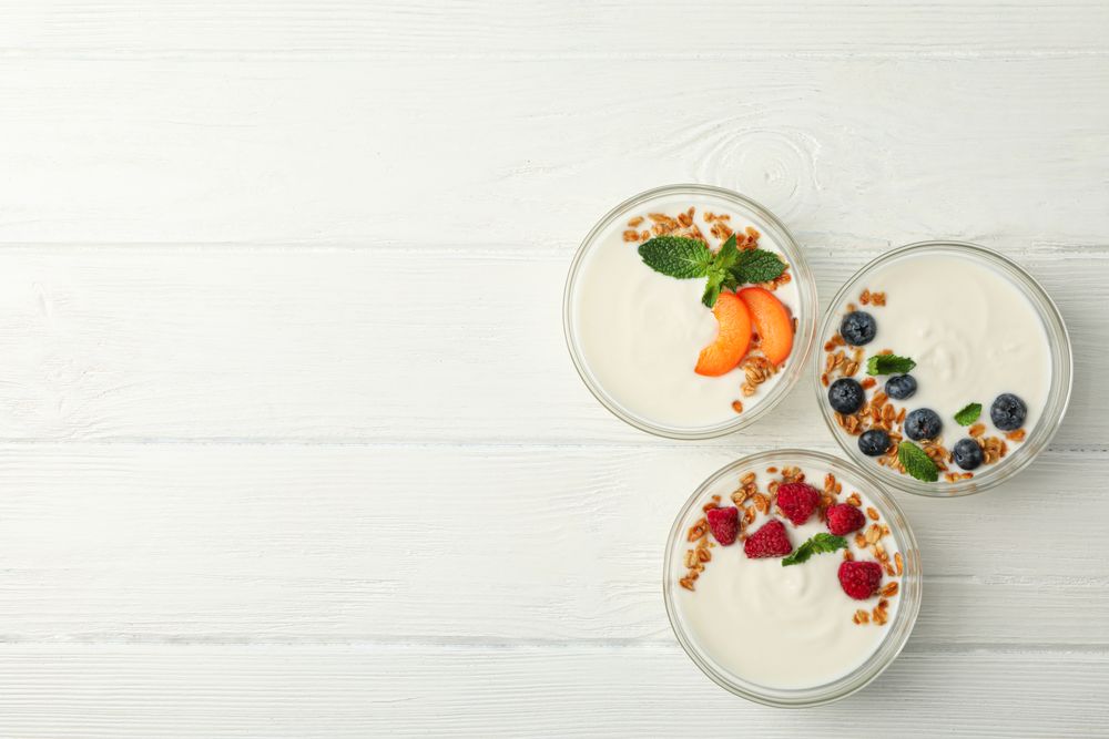 Flat lay composition with yogurt desserts and ingredients on wooden background