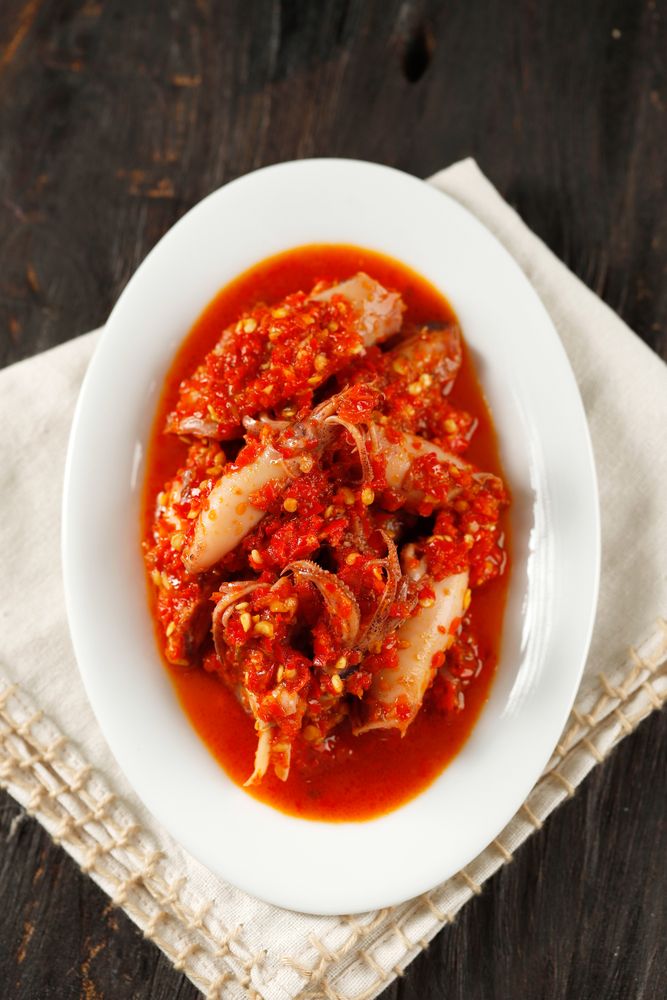 Spicy salted squid dish on wooden table, vertical