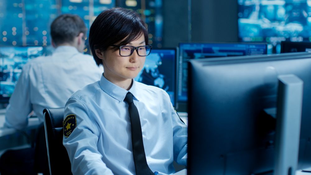 In the Security Command Center Officer at His Workstation Monitors Multiple Screens for Unlawful Infiltration.