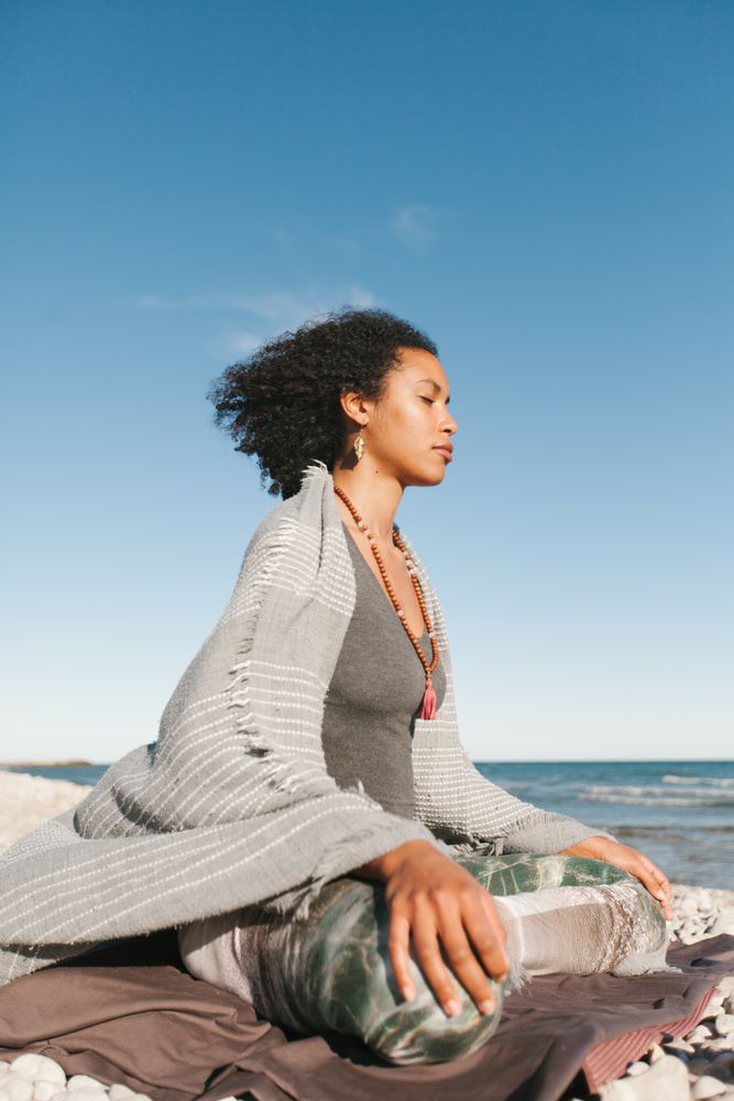 Sportive woman sitting on sandy beach in asana