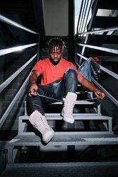 Stylish man in boots sitting on stairs