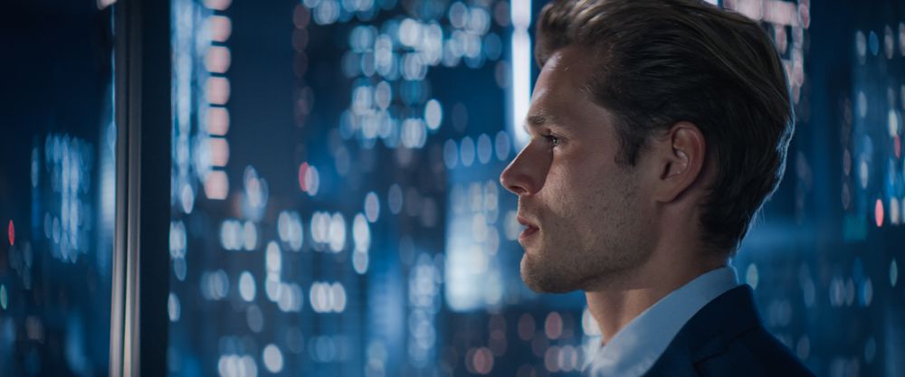 Close Up Portrait of Businessman in a Suit Standing Next to Window in Big City Office with Skyscrapers Late At Night.