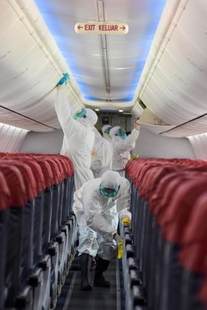 People in PPE and facemask sanitizing the interior of plane
