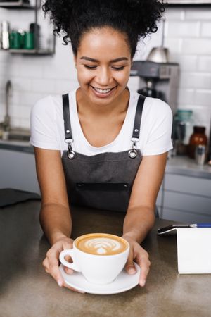 Smiling barista looking down at cappuccino