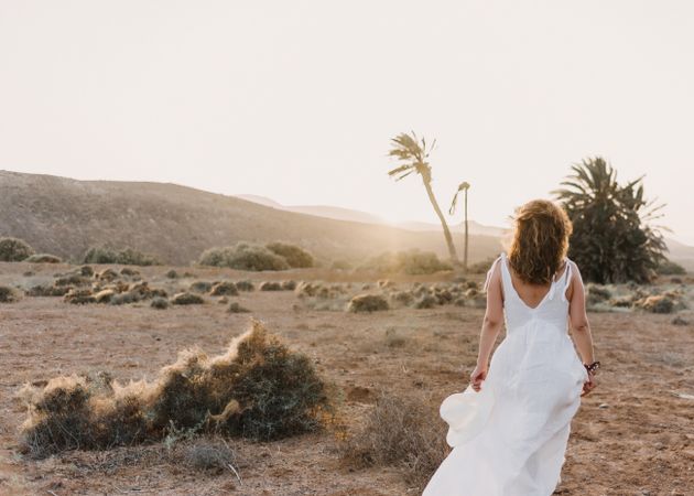 Woman in white dress in dry field in sunlight
