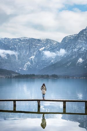 Woman on bridge in alpine scenery standing on bridge on lake