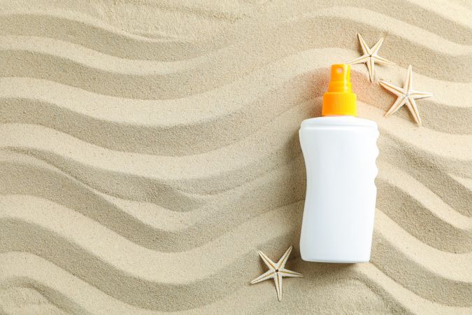 Clear sea sand with sunscreen and starfishes, space for text. Summer vacation background