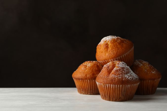 Tasty muffins on wooden table against brown background