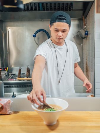 Young male decorating prepared Japanese dish