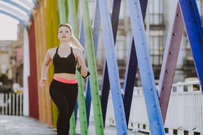 Woman with earphones running on street
