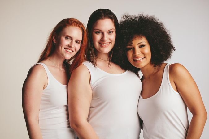 Group of diverse models wearing tank tops against light colored background
