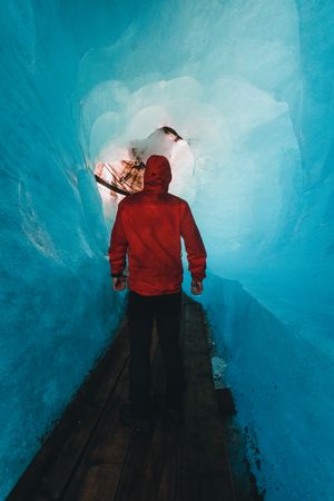 Back view of person in red jacket walking in an frozen cave