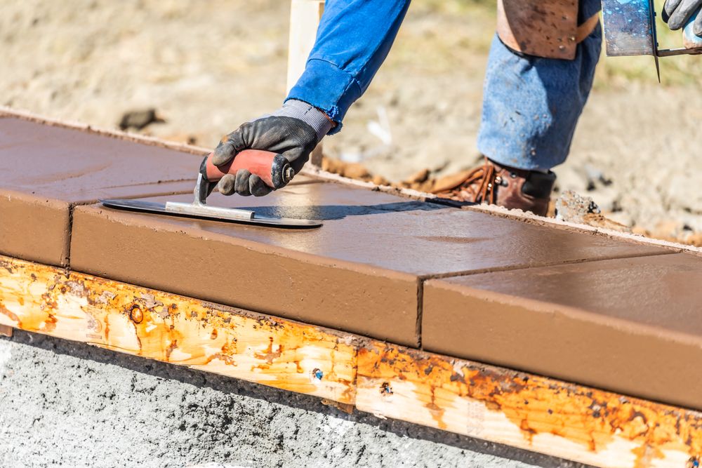 Construction Worker Using Trowel On Wet Cement Forming Coping Around New Pool