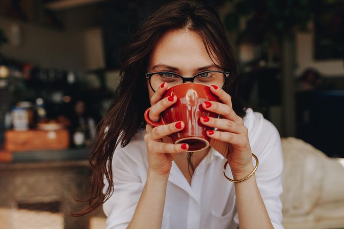 Close up portrait of young woman drinking coffee at cafe