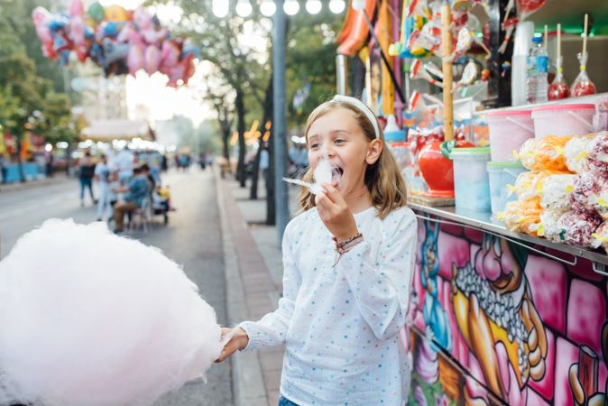 Cheerful girl eating cotton candy on street
