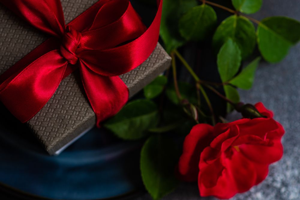 Table setting with red rose and gift
