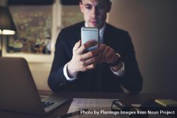 Professional businessman texting at his desk while working at night 5qrOj4