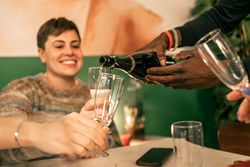 Close-up of hands pouring sparkling wine into a glass during a festive toast.