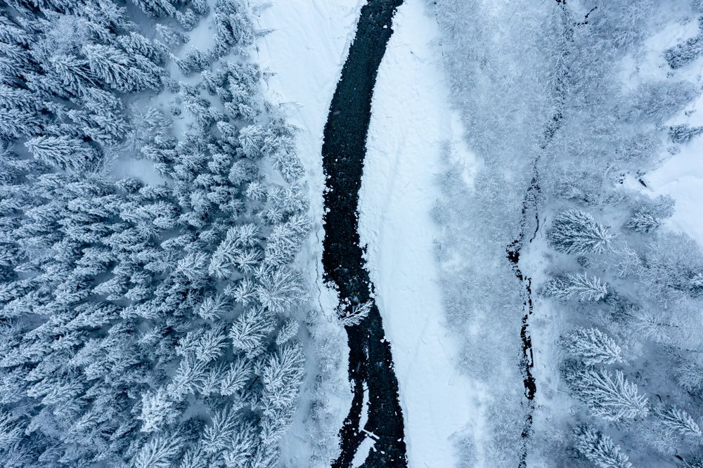 Drone aerial image with snowy forest and river in the Bavarian Alps, Germany