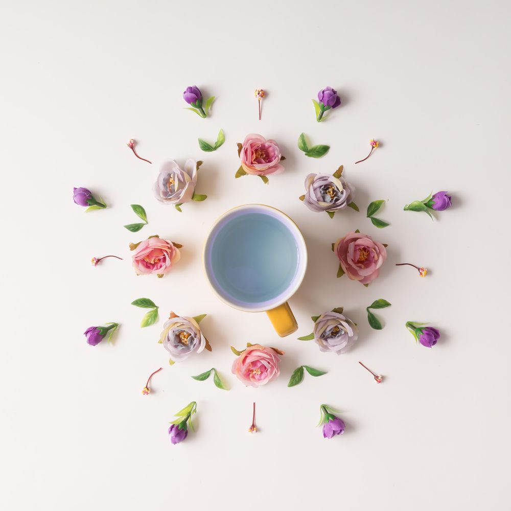 Circular flower arrangement surrounding mug on light background