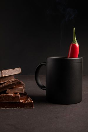 Chocolate near mug with hot drink and pepper